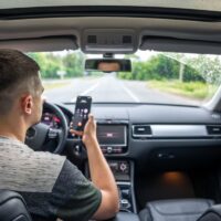 Businessman talking on cell phone while driving, a view from inside the car.